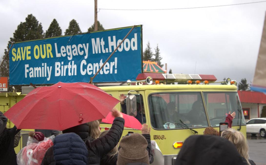 A sign on top a fire engine reads "save our legacy mount hood family birth center.