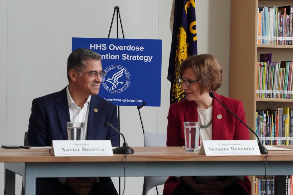 A man and a woman sit at a table, talking.