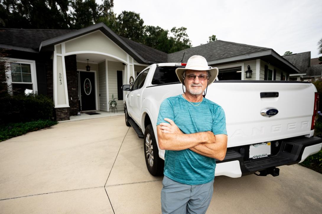 Man stands in driveway in front of pickup truck.
