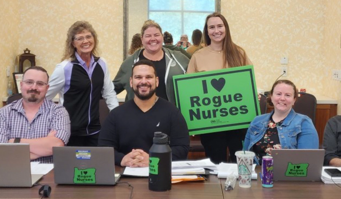 Six people at a table with sign saying 'I love Rogue Nurses'