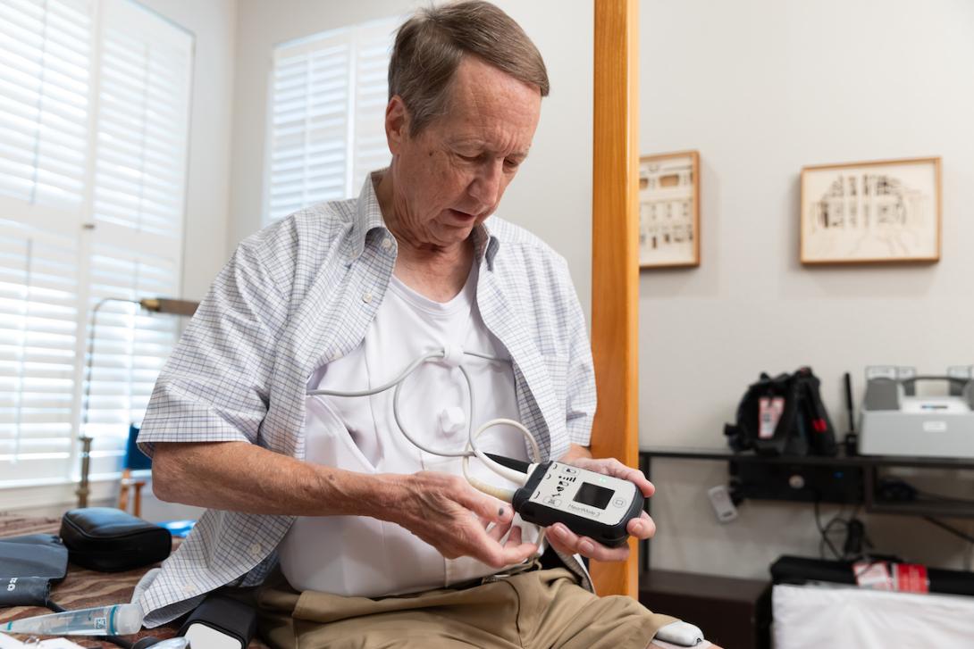 heart pump patient man holds gauge of some kind while sitting down