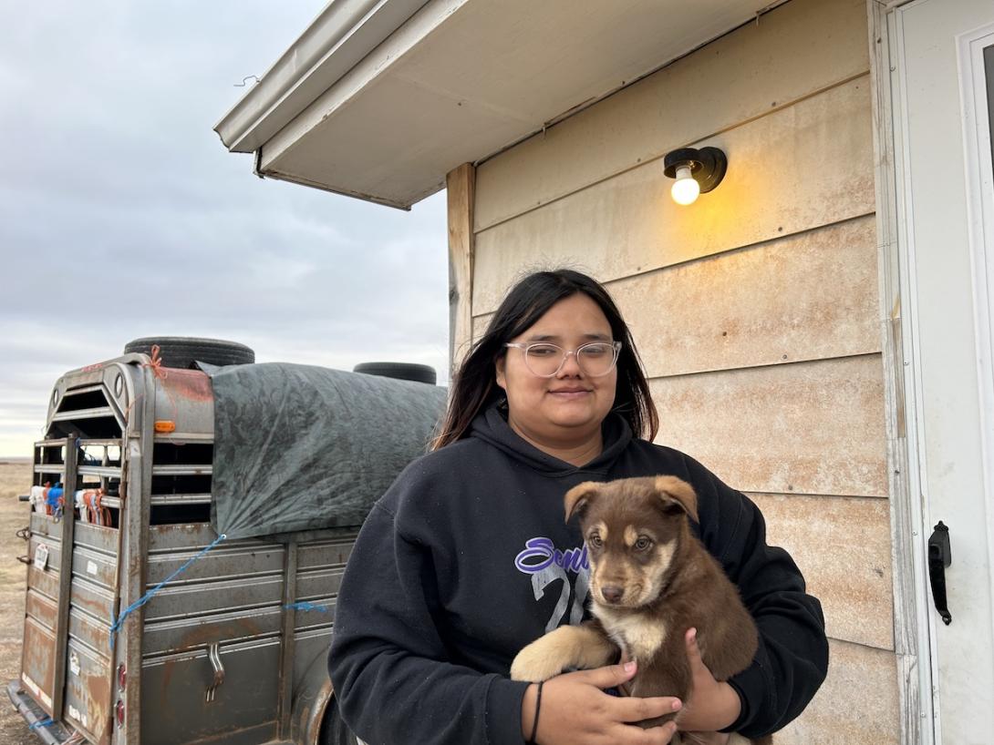 Young woman holds puppy outside house