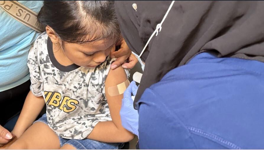 A worker applies an adhesive bandage to a child at a vaccination clinic in Minneapolis’ Corcoran Park in August 2023 A worker applies an adhesive bandage to a child at a vaccination clinic in Minneapolis’ Corcoran Park in August 2023