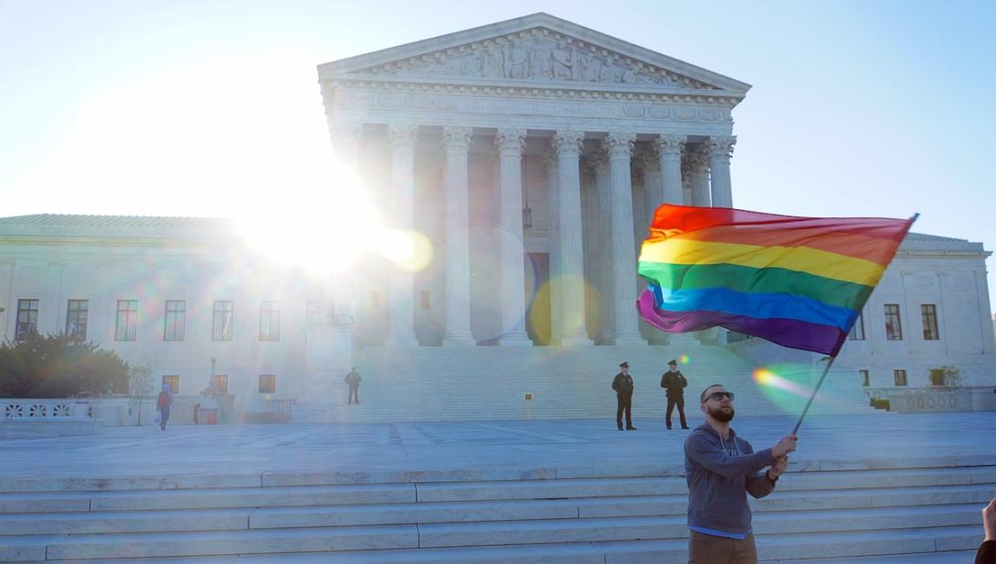 Person waves rainbow flag outside of the U.S. Supreme Court