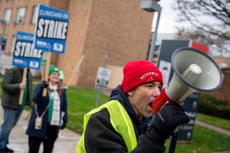 Joe Cartino, labor representative with the Oregon Nurses Association, leads chants for striking advanced practice providers, which include medical professionals like nurse practitioners, physician assistants and others, outside Legacy Emanuel Medical Center in Portland, Ore., on Dec. 3, 2025.  Eli Imadali / OPB
