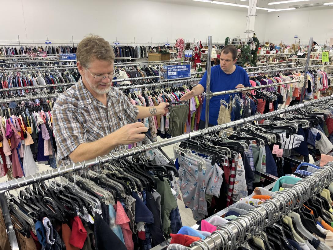 Medicaid participant Sam Walker (right) sorts clothing at a Goodwill store in Ottumwa, Iowa, with Andy Koettel, a caregiver paid through a Medicaid waiver program that helps people with disabilities. 