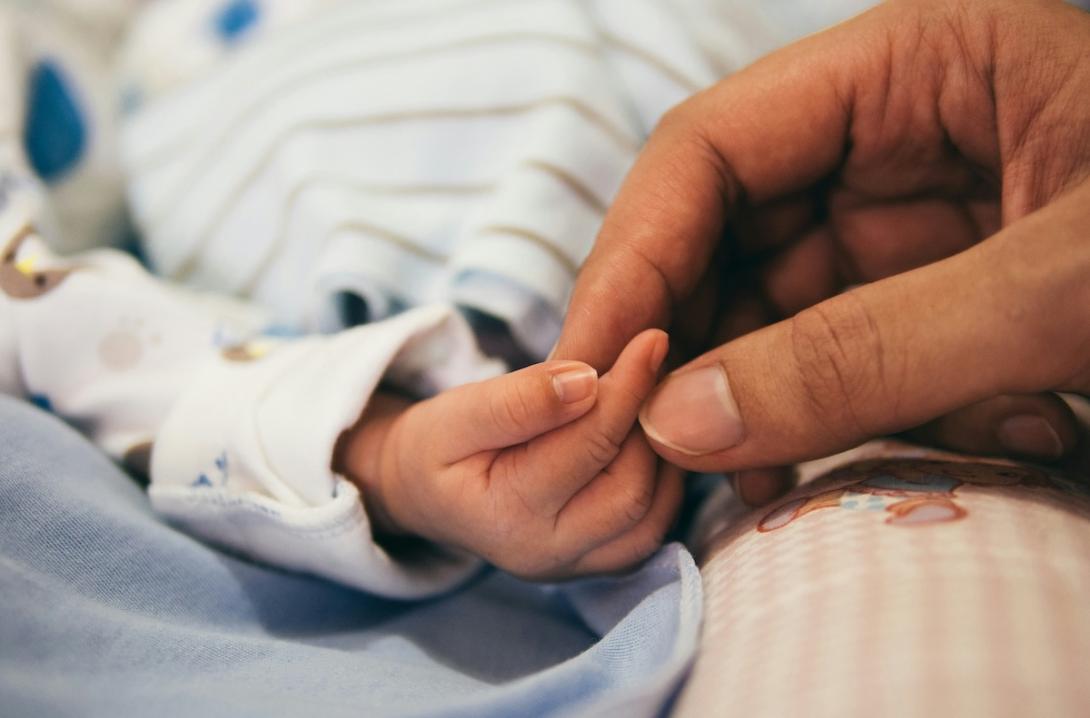 Newborn baby's hand with adult hand.