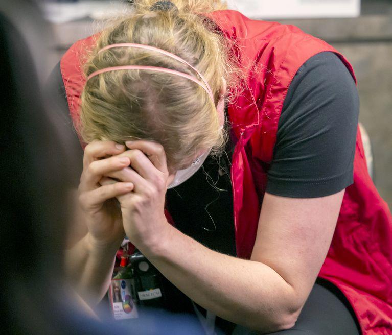 Nurse in scrubs bent over and crying.