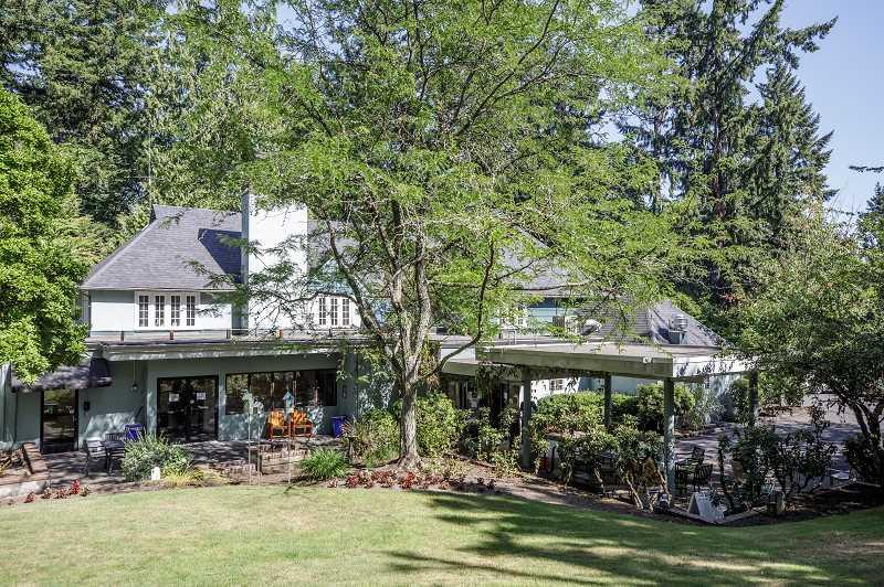 A two story house with a green lawn and garden.