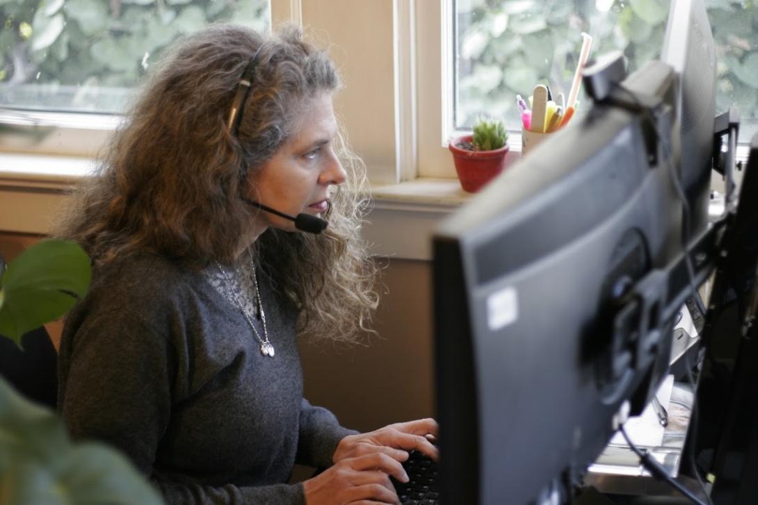 woman wearing telephone headset peers at computer monitor