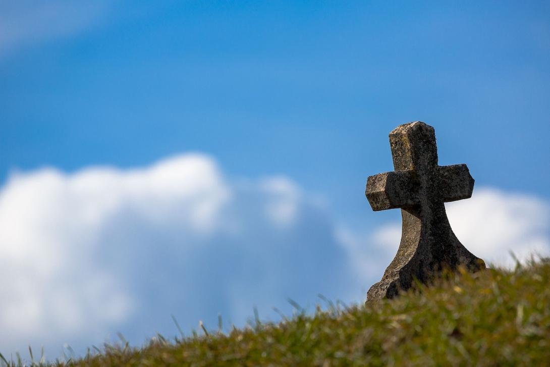 Old cross-shaped grave stone on a hill.
